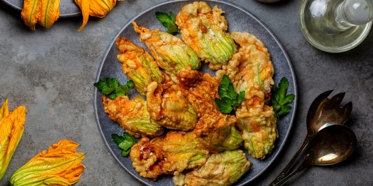 su tavolo da cucina di ardesia, piatto nero con fiori di zucca fritti e attorno fiori di zucca