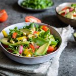 su tavolo di marmo, ciotola con un'insalata con avocado, mais e pomodori