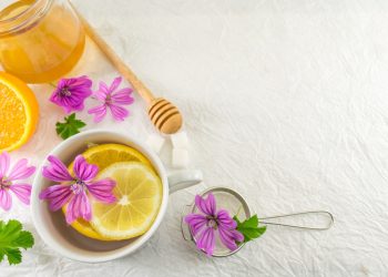 Una tazza di tisana alla malva con un barattolo di miele accanto