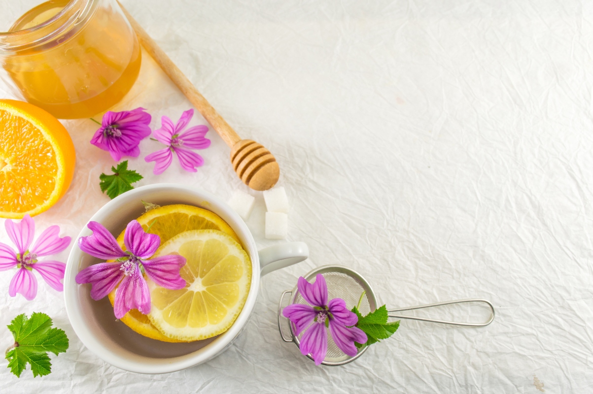 Una tazza di tisana alla malva con un barattolo di miele accanto