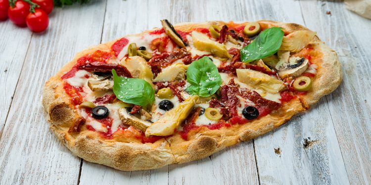 su tavolo di legno, pinsa romana con pomodori, funghi e rucola , accanto pomodorini