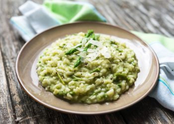 su base di legno piatto tondo grigio con risotto agli asparagi