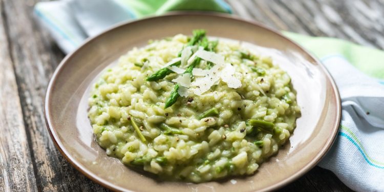 su base di legno piatto tondo grigio con risotto agli asparagi