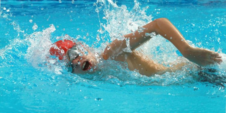 uomo in piscina che esegue un allenamento nuoto intermedio con cuffia e occhialetti da piscina
