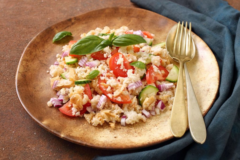Panzanella: insalata di pane e verdure, fresca e leggera 5 un piatto di legno tondo con una porzione di panzanella fresca