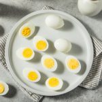 in primo piano delle uova sode tagliate a metà su un piatto bianco