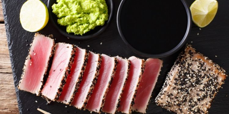ricette con tonno: su vassoio nero fette di tonno scottato e ciotola con guacamole