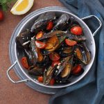 una casseruola con due manici piena di cozze alla tarantina