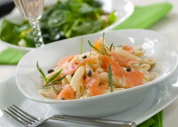 tavola apparecchiata con un piatto di pasta al salmone e una forchetta