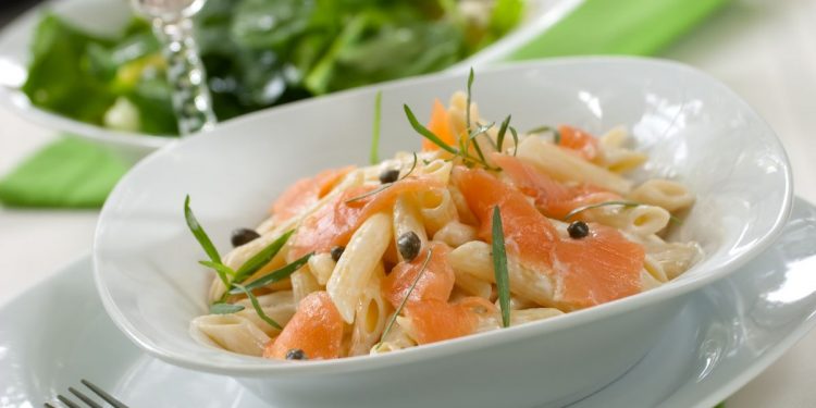 tavola apparecchiata con un piatto di pasta al salmone e una forchetta