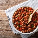 Fagioli all’uccelletto: la ricetta toscana saporita con video 1 In primo piano su un tavolo di legno ci sono dei fagioli all'uccelletto in un tegame.
