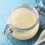 un barattolo pieno di latte condensato su un piano azzurro