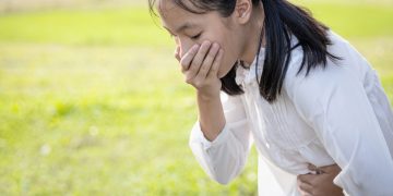una bambina che si tiene con le mani la bocca e la pancia perché soffre di alitosi