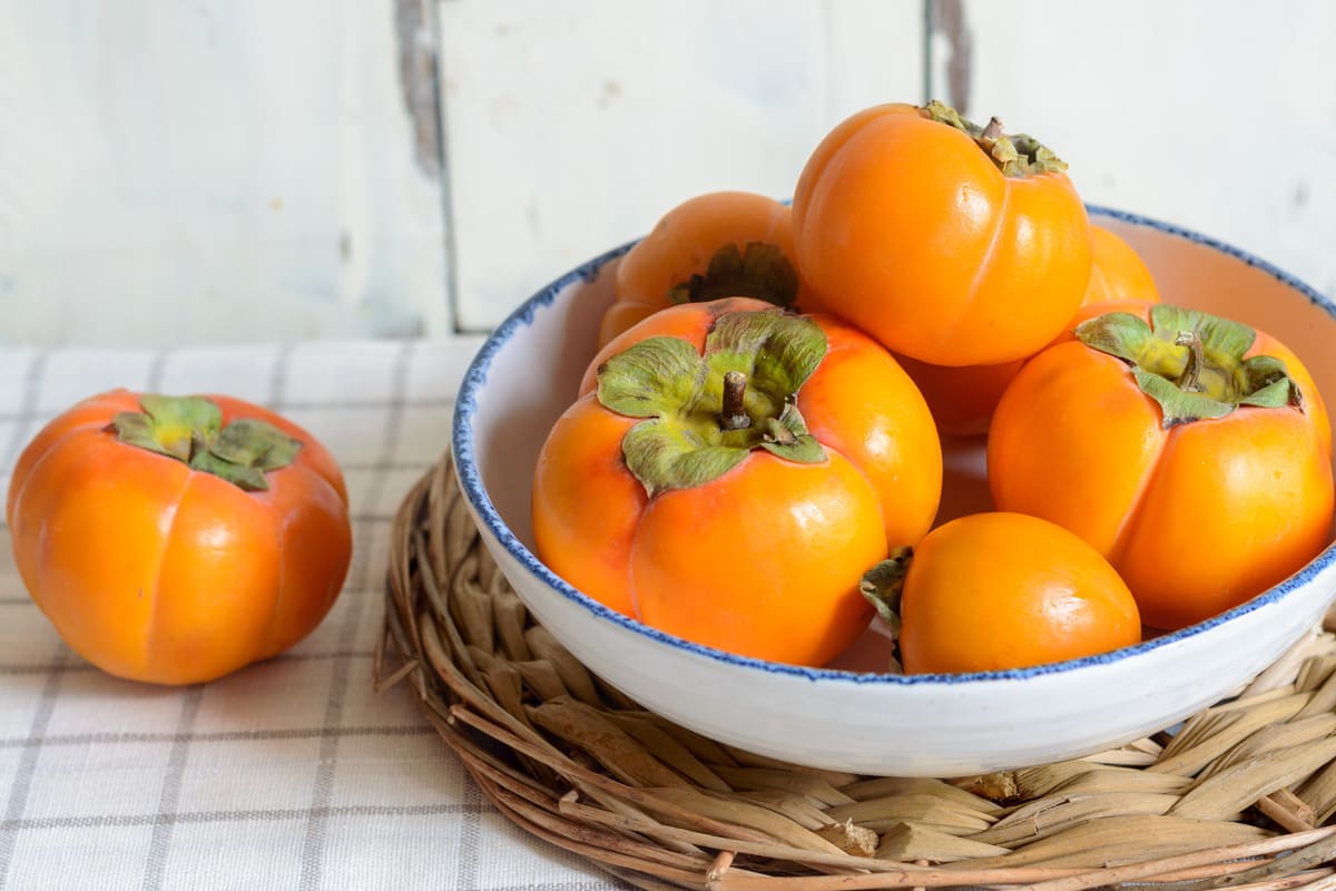 Cachi maturi raccolti in una ciotola di ceramica.