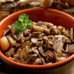 ciotola di coccio piena di funghi trifolati con prezzemolo