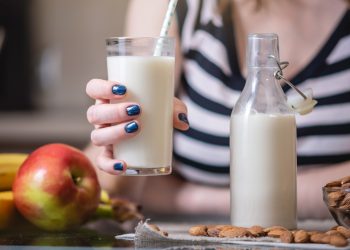 Una giovane donna tiene in mano un bicchiere di latte di mandorle