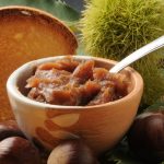 Marmellata di castagne: la versione light senza zucchero e la ricetta classica della nonna 2 coppa di legno con marmellata di castagne e cucchiaino, castagne sparse e una fetta biscottata