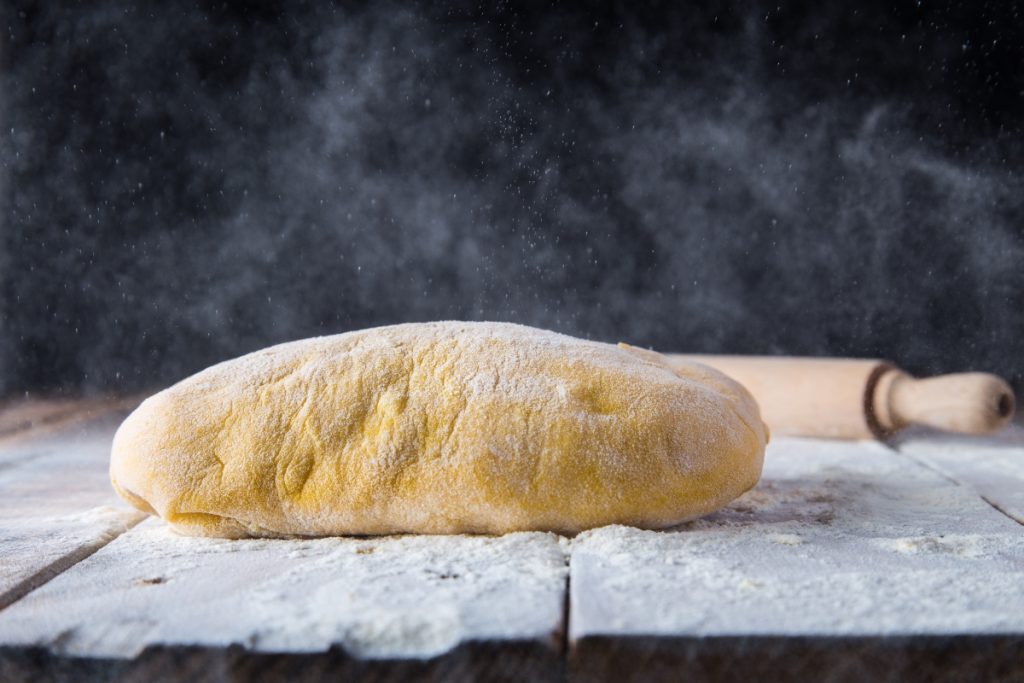 su piano di lavoro infarinato un impasto di pasta frolla e un mattarello