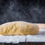 su piano di lavoro infarinato un impasto di pasta frolla e un mattarello