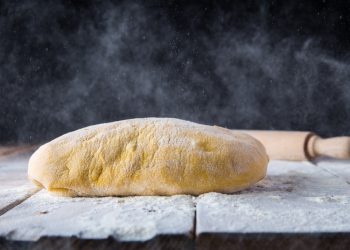 su piano di lavoro infarinato un impasto di pasta frolla e un mattarello