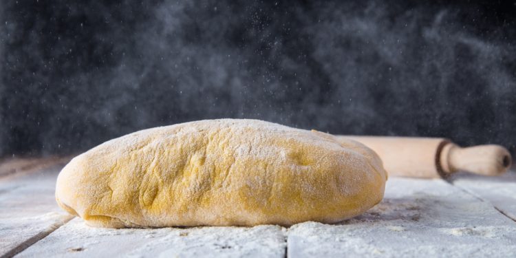 su piano di lavoro infarinato un impasto di pasta frolla e un mattarello