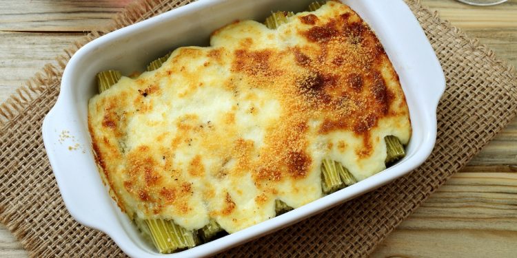 su tavolo di legno sotto piatto con contenitore bianco rettangolare che contiene cardi gratinati
