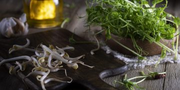 dei germogli di soia freschi su un tagliere nero