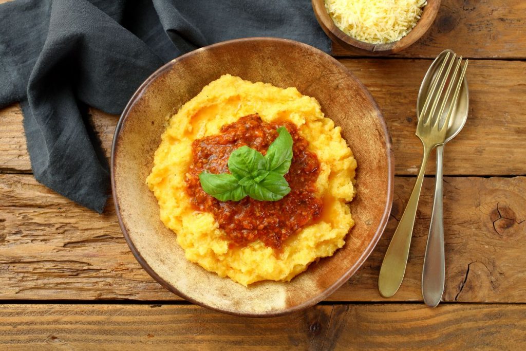 Come fare la polenta in casa, calorie e ricette tutte da gustare 1 su base di legno un piatto di legno colmo di polenta con il sugo