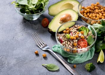 Piatto con ceci, insalata e avocado. Sul tavolo ingredienti per preparare ricette vegetariane