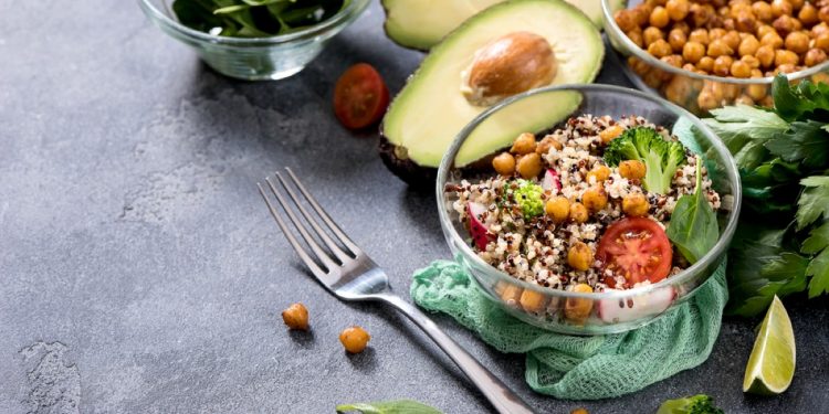 Piatto con ceci, insalata e avocado. Sul tavolo ingredienti per preparare ricette vegetariane