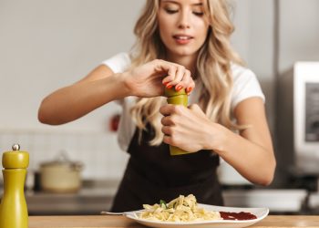 Donna che usa macina pepe sopra un piatto di pasta