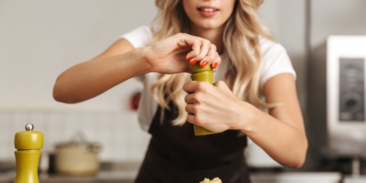 Donna che usa macina pepe sopra un piatto di pasta