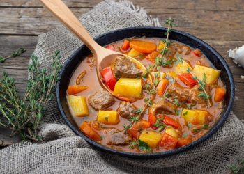 un piatto di gulash con un mestolo di legno