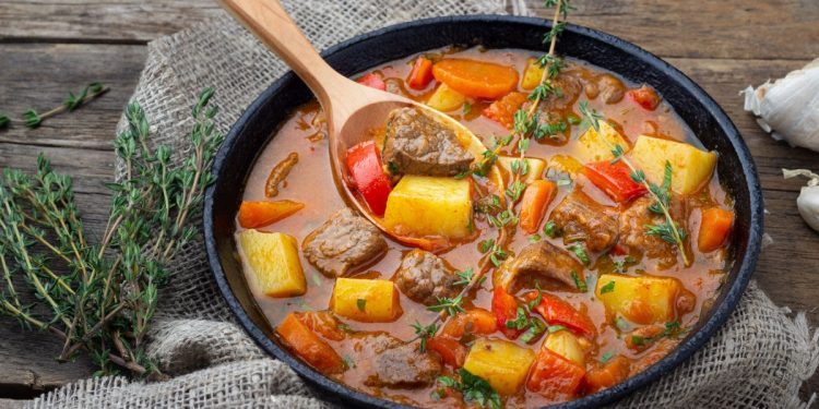 un piatto di gulash con un mestolo di legno
