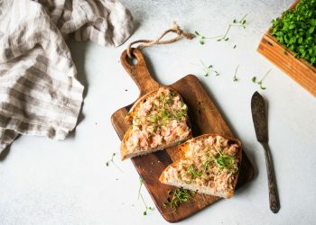 su tavolo di marmo, tagliere con 2 tartine di mousse di salmone, un coltello, un canovaccio e prezzemolo tritato