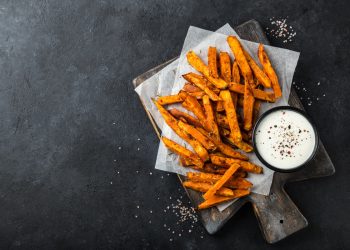bastoncini di patate dolci fritte su un tavolo con accanto una ciotolina con della salsa