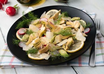 su tavola apparecchiata piatto tondo nero con Insalata di carciofi