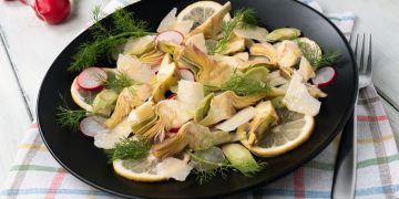 su tavola apparecchiata piatto tondo nero con Insalata di carciofi
