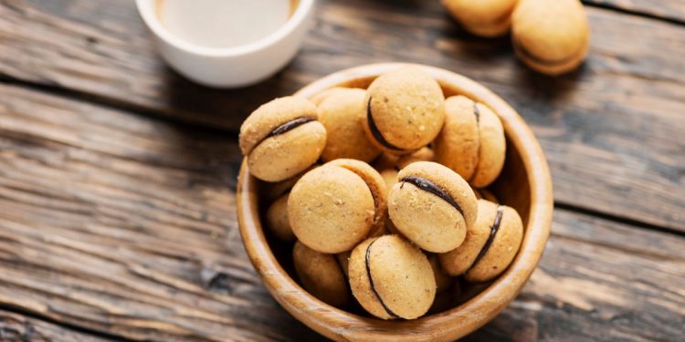 su base di legno una ciotola piena di baci di dama i biscotti tipici piemontesi