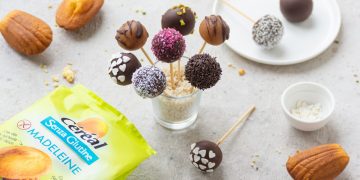 un bicchiere con t bastoncini con cake pops di diversi gusti e colori