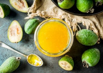 alcuni frutti di Feijoa su un tavolo con accanto un bicchiere con il succo di questo frutto