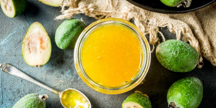 alcuni frutti di Feijoa su un tavolo con accanto un bicchiere con il succo di questo frutto