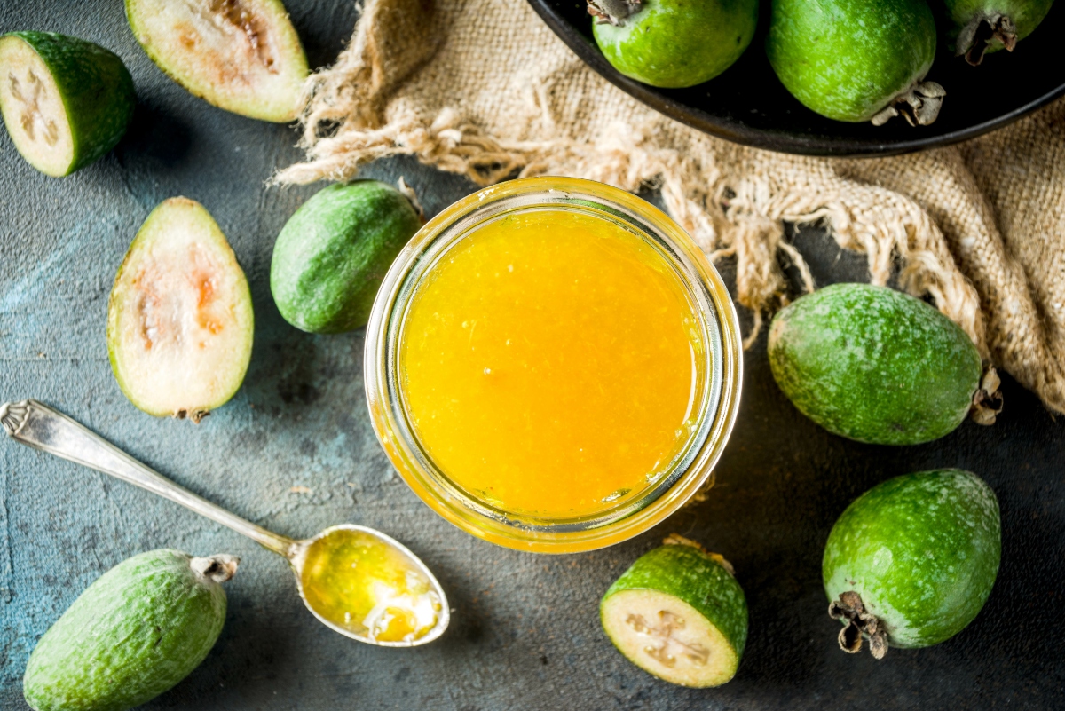 alcuni frutti di Feijoa su un tavolo con accanto un bicchiere con il succo di questo frutto