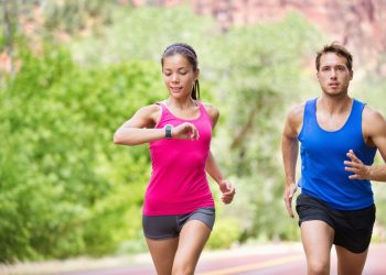 coppia che corre mentre la donna guarda il cardiofrequenzimetro