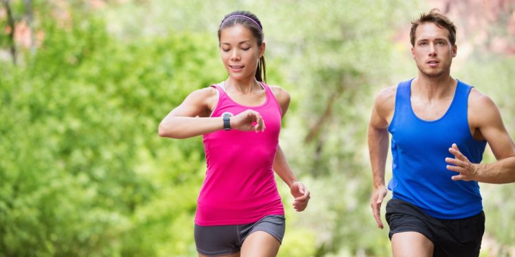 coppia che corre mentre la donna guarda il cardiofrequenzimetro
