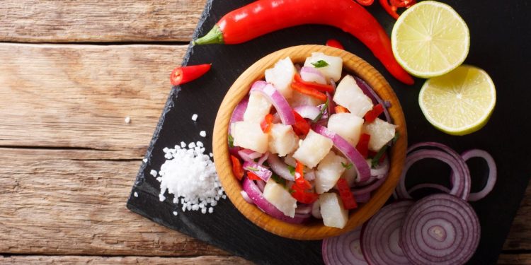 vassoio bero quadrato con ciotola di ceviche, fette di cipolla, spicchi di limone e peperoncini