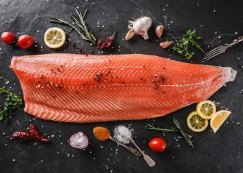 grande fetta di salmone crudo al centro di pomodorini e limone
