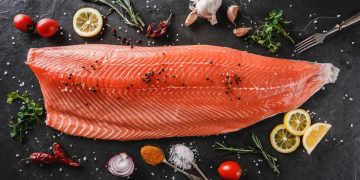 grande fetta di salmone crudo al centro di pomodorini e limone