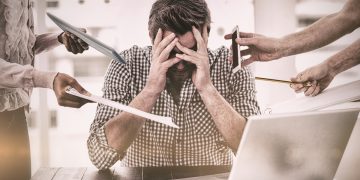 un uomo seduto al pc in preda allo stress e al cortisolo alto