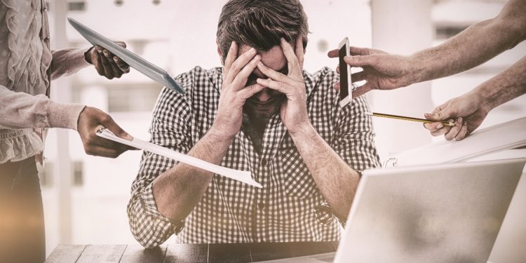 un uomo seduto al pc in preda allo stress e al cortisolo alto